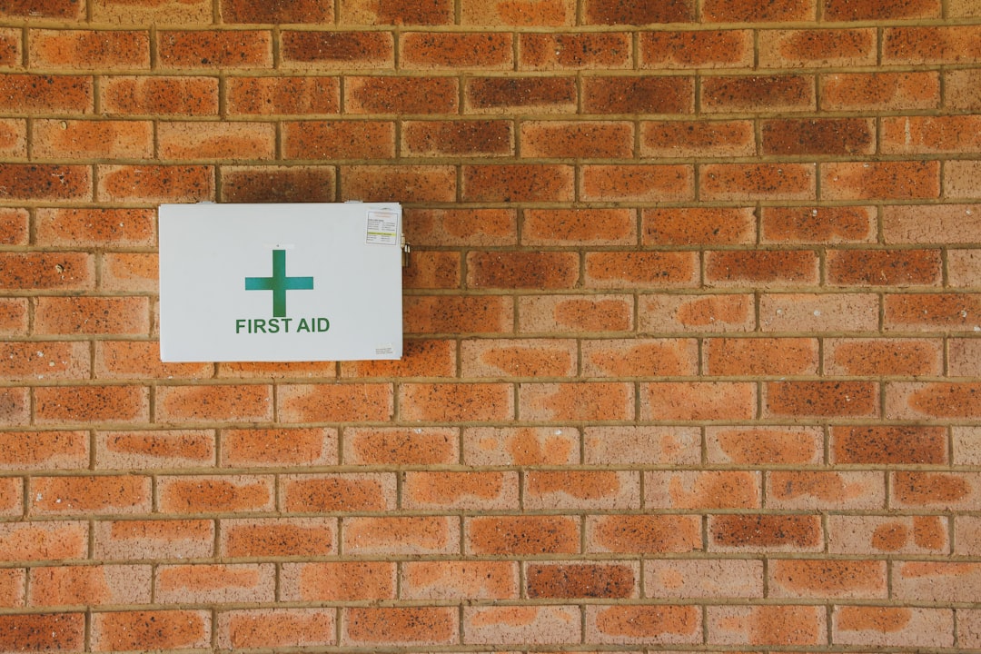 A close-up of a first aid kit with bandages, antiseptic wipes, and a pair of scissors, placed on a wooden surface.
