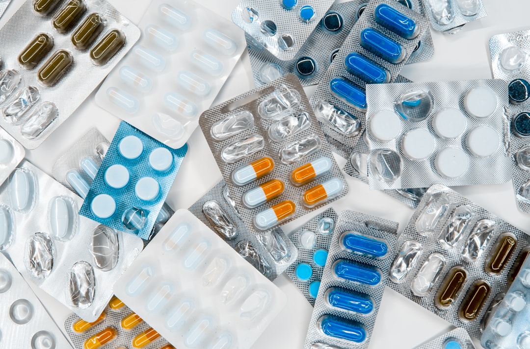 A close-up of various medicine bottles and packages with visible expiration dates, arranged neatly on a countertop.