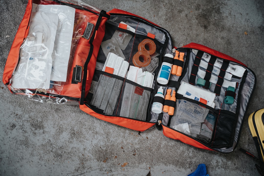 A neatly organized travel first aid kit with essential health supplies, including bandages, antiseptic wipes, and medications, set against a backdrop of travel gear like a backpack and map.